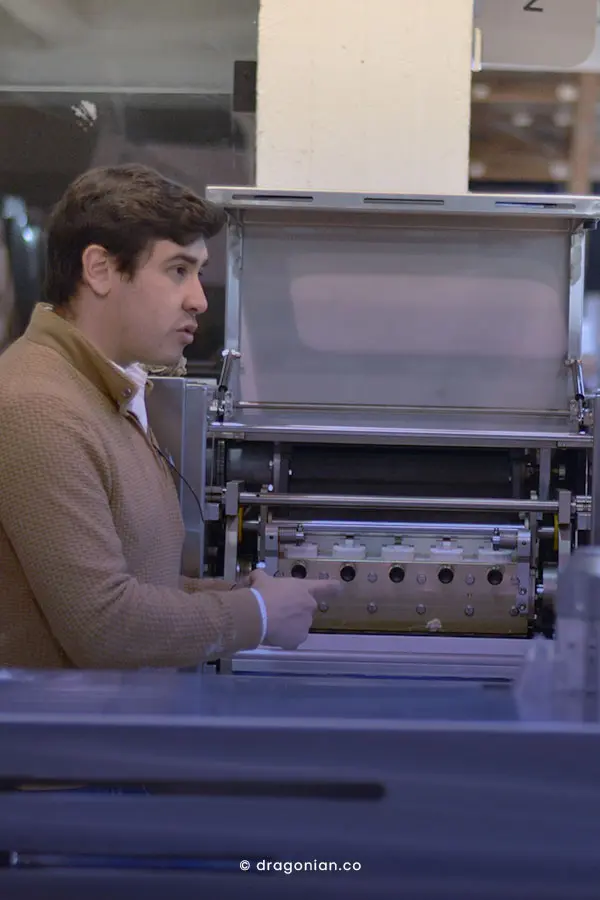 Joven enseñando el proceso de una máquina boleadora y divisora Industrial para panadería. Fotografía por dRaGoNian.