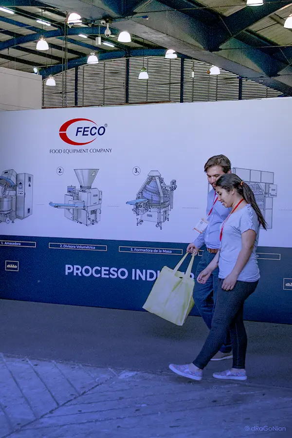 Chef sonriente con los brazos abiertos y al fondo un backing con ilustraciones de equipos industriales para Panadería de la marca Polin